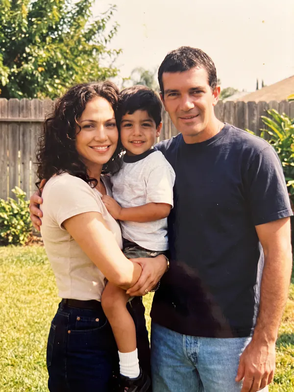 Foto de família dos anos 90 de um menino no colo de Jennifer Lopez, com Antonio Banderas ao lado