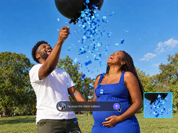 Couple in a park laughing as a black balloon bursts with blue confetti, with the prompt he pops the black balloon