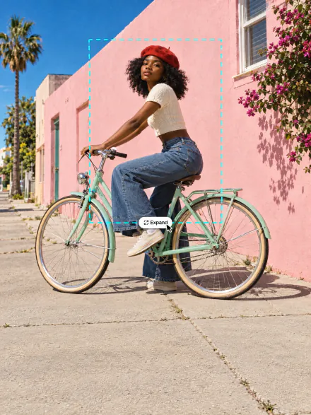 Woman on a mint bicycle by a pink wall, the photo expanded beyond the dashed frame of the original