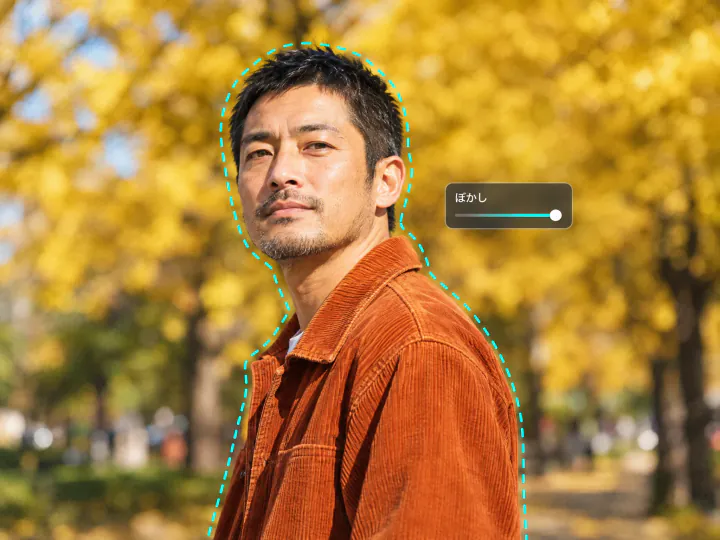 イチョウ並木の背景をぼかした男性のポートレート。輪郭を囲む点線と「ぼかし」のスライダー