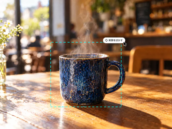 カフェのテーブルに置かれたマグカップ。背景がぼけ、マグを囲む点線と「背景をぼかす」ボタン
