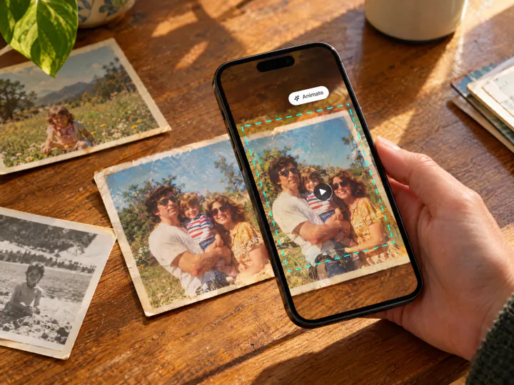 Phone held over old family prints on a table, playing one of them as a video