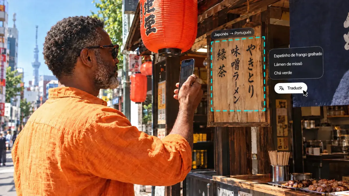 Homem fotografando um cardápio japonês escrito à mão em uma barraca de comida em Tóquio, com o cardápio selecionado e traduzido para o português